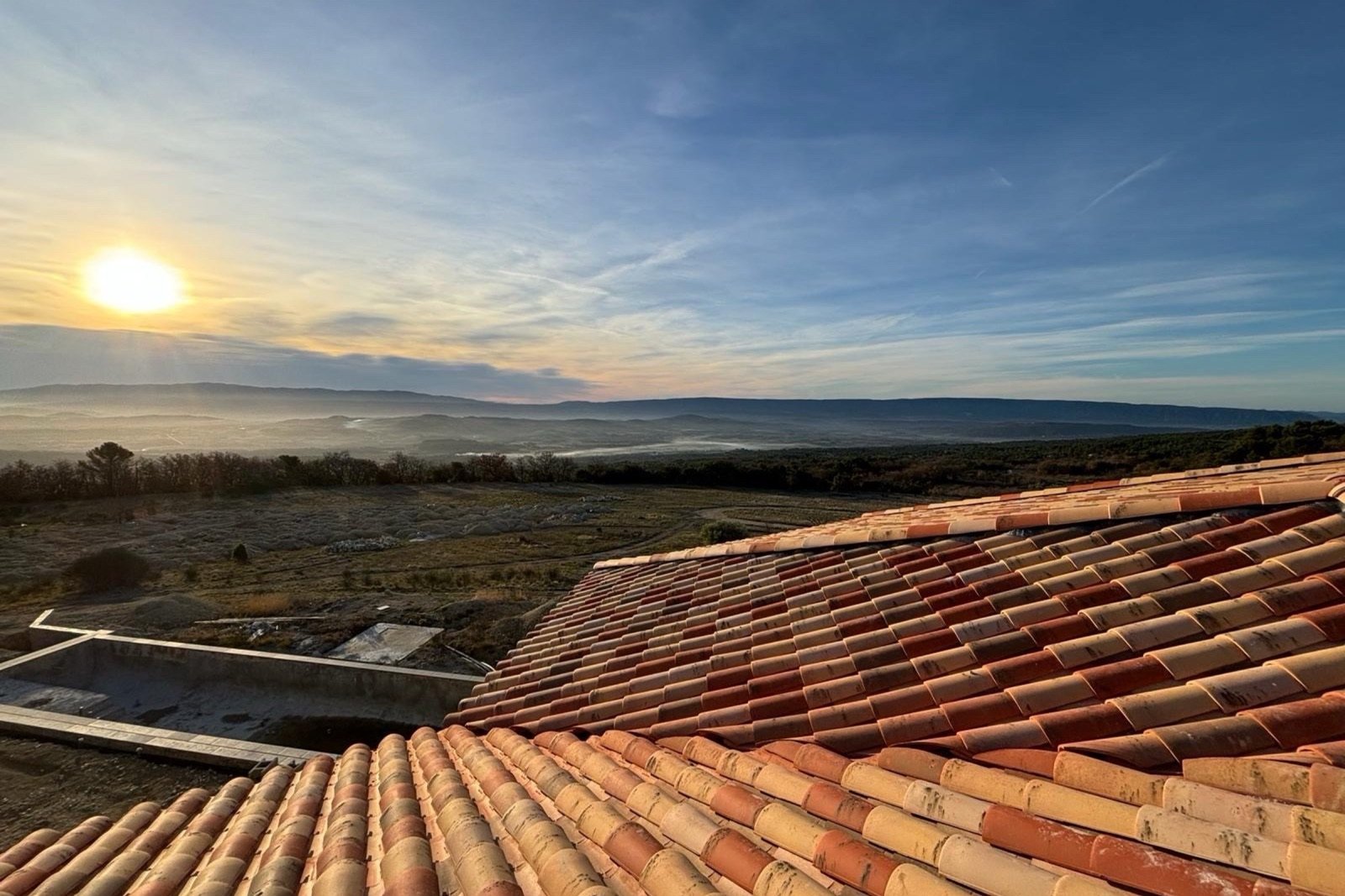 Toiture en tuiles au coucher du soleil, chantier Amblard Construction
